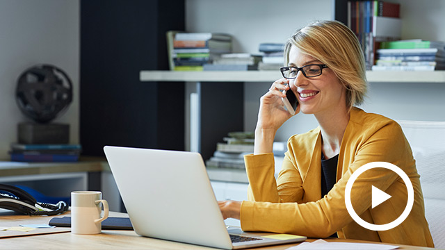 A real estate women agent sitting in front of laptop and talking on phone and smiling